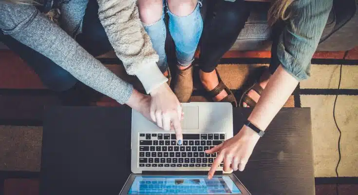 three person pointing the silver laptop computer