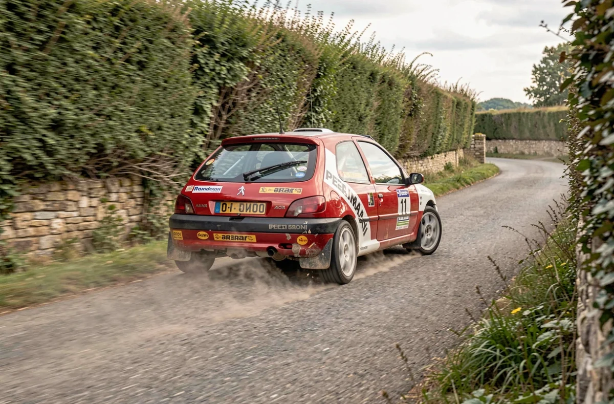 Peugeot 106 Maxi rouge et blanche en pleine action dans un virage sur une spéciale de rallye amateur