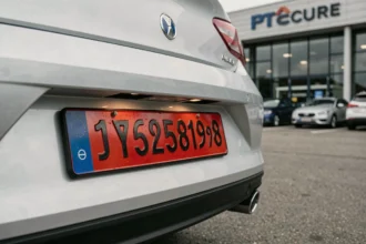 Plaque d'immatriculation rouge temporaire fixée sur un véhicule neuf dans une concession automobile en France